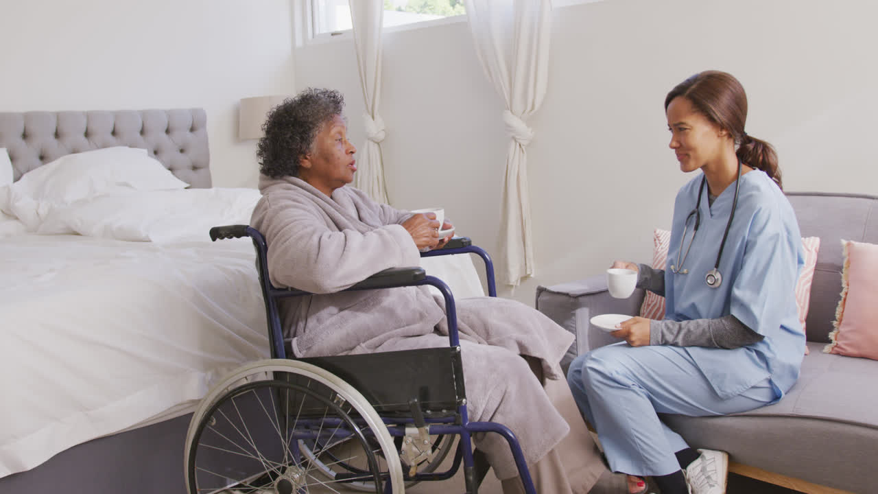 mujer de raza mixta siendo visitada en casa por una enfermera. distanciamiento social y aislamiento en cuarentena