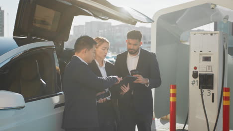 profesionales de negocios discutiendo el proyecto en la estación de carga de automóviles eléctricos