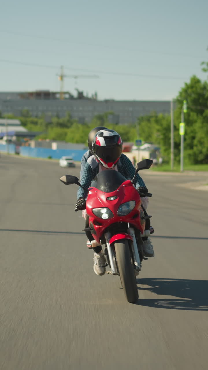 dos hermanas en una bicicleta eléctrica roja navegan a lo largo de una carretera urbana, con una vista borrosa de personas caminando por el camino y coches acercándose por detrás