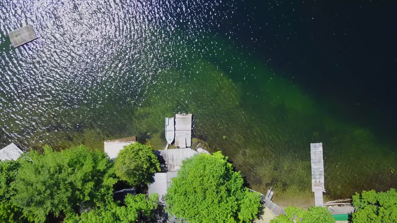 UHD drone reveal shot of an aluminum boat moored to a dock on a deep lake in Ontario Canada