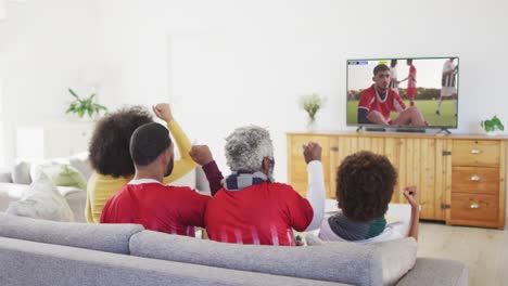 African-american-family-watching-tv-with-diverse-male-soccer-players-playing-match-on-screen