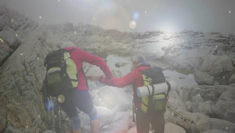 행복한 백인 노인 커플이 산에서 빠르게 움직이는 눈조각을 따라 하이킹하고 있습니다.