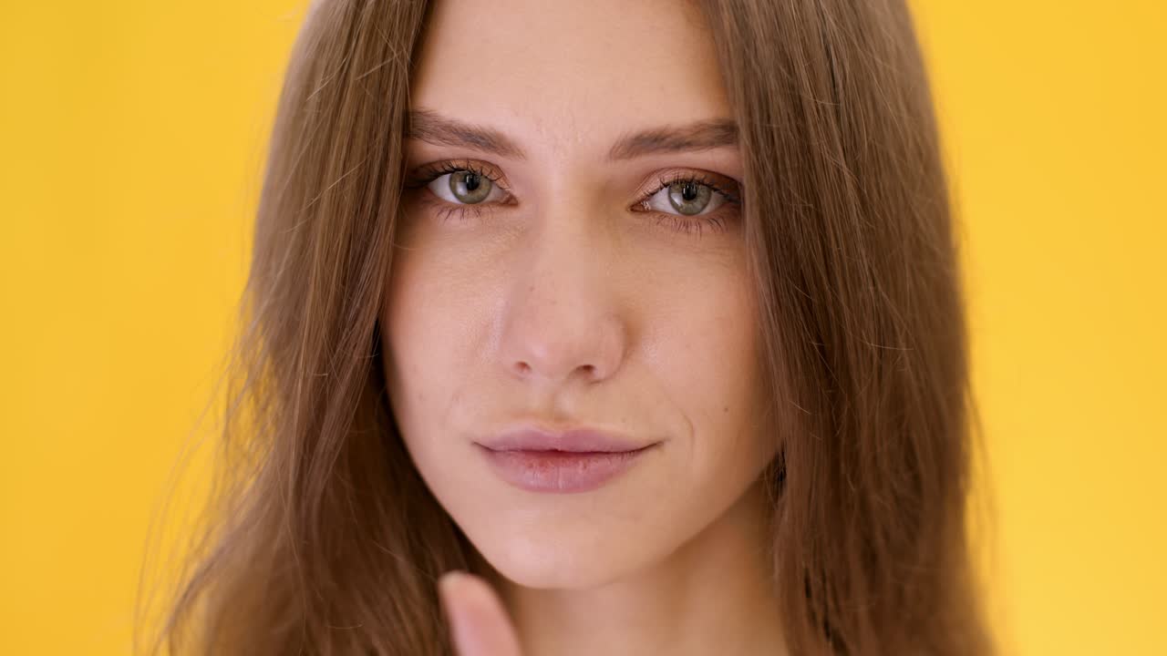 Donna che fa un gesto di silenzio davanti a uno sfondo giallo