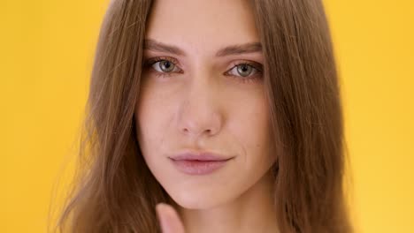 woman with hush gesture in front of yellow background