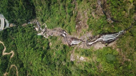 Direkt-über-Einem-Wasserfall,-Der-Zu-Wanderwegen-Und-Einem-Schlammigen-Fluss-Führt