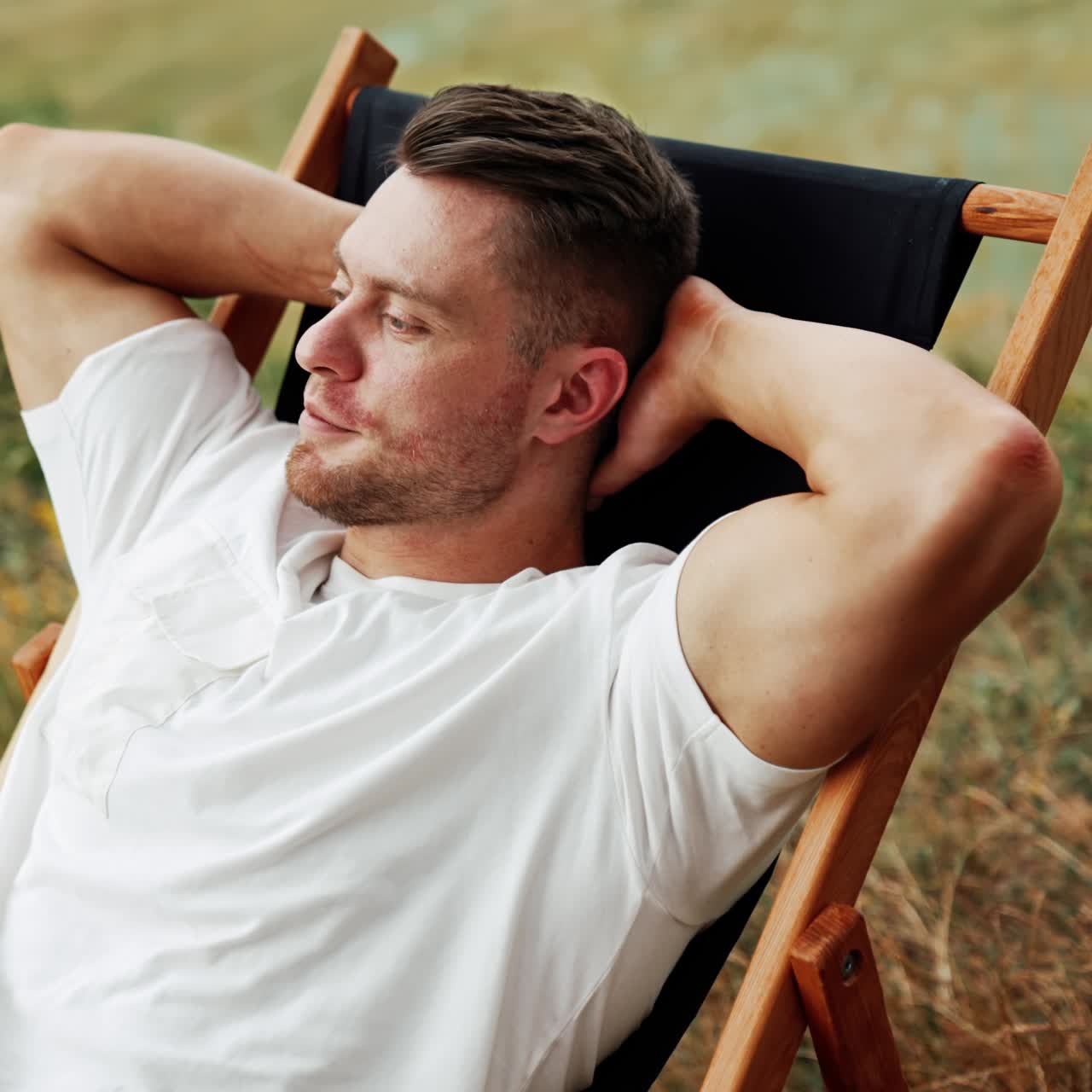 Caucasian man enjoying rest in the nature. Man sits comfortably in a folding chair, looking around
