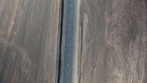 aerial drone shot of car driving on a desertic road from top