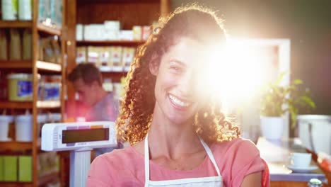 personal femenino sonriente de pie con las manos en la cadera en la sección de comestibles