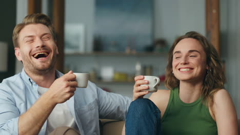 laughing lovers coffee cups holding at home closeup. carefree spouses having fun