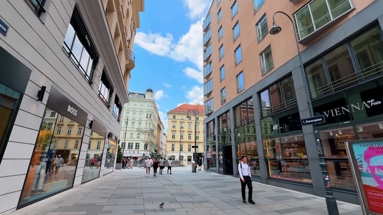 Vienna, Austria - June 9, 2025: Large window cases of modern shops. A walk by the pedestrian street in Vienna, Austria