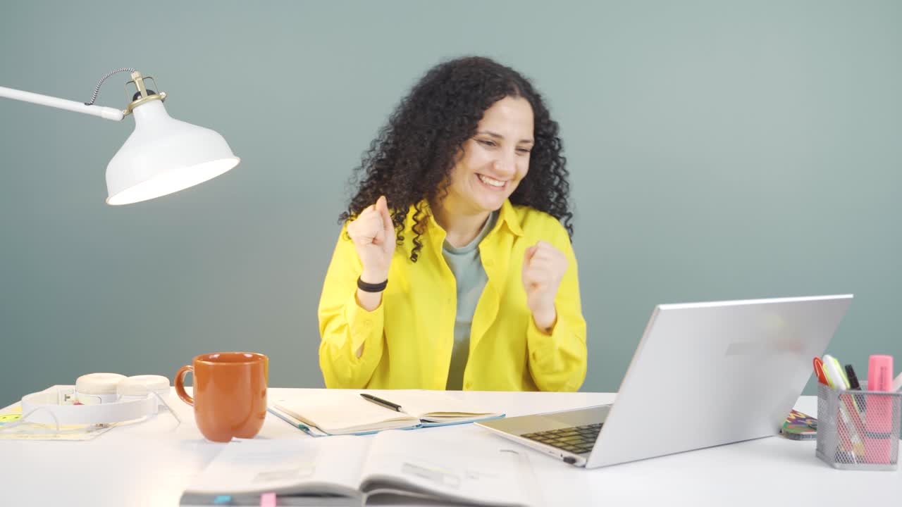 mujer joven mirando la computadora portátil aplaudiendo.