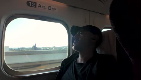 tourist enjoying comfortable ride on shinkansen bullet train, admiring japanese landscape through window