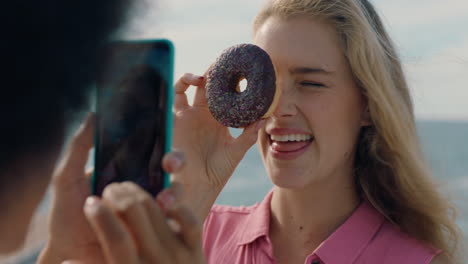 beautiful woman posing with donut on beach best friend taking photos using smartphone sharing weekend by seaside on social media enjoying summertime fun 4k