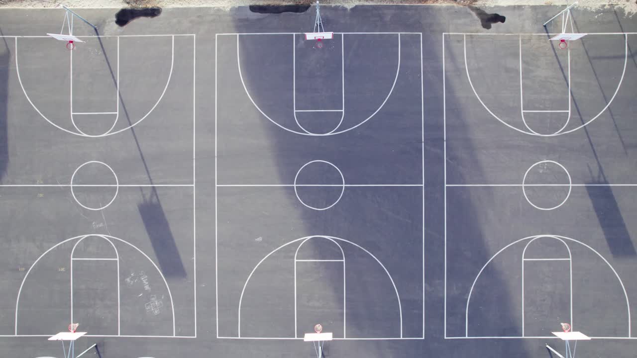Drone top-down shot of three empty outdoor basketball courts at a school in Southern California. Taken in early summer morning