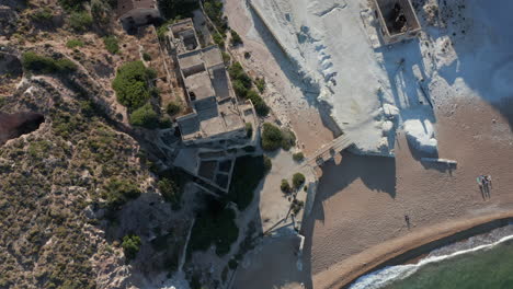 Antena-Arriba-Abajo-Vista-De-Pájaro-De-Un-Pueblo-De-Fábrica-Abandonado-En-La-Playa-En-La-Isla-Griega