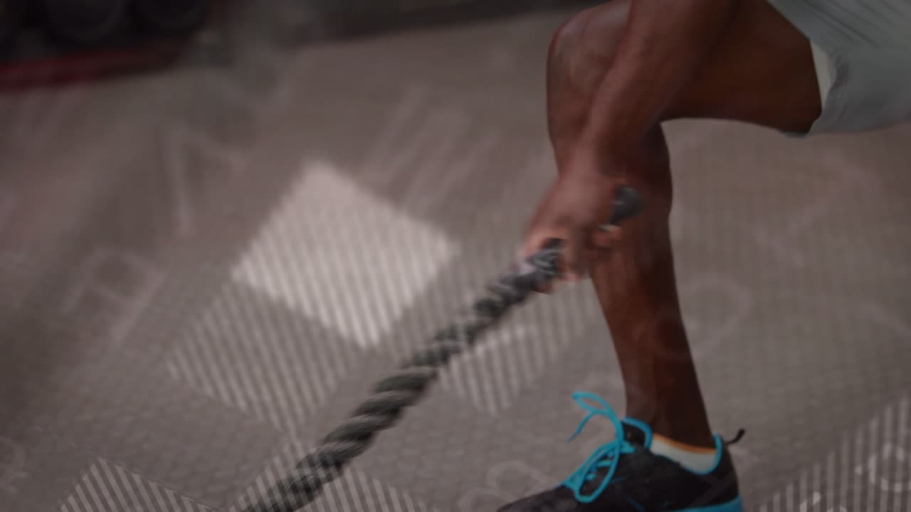 Male fitness athlete dropping low, gripping rope and driving waves with digital overlays syncing