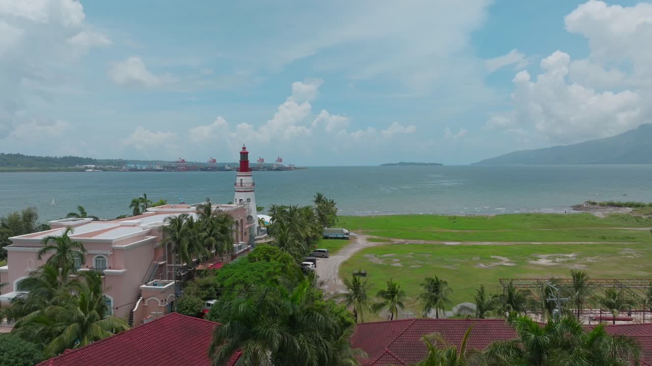 A stunning drone shot captures the vast ocean stretching toward the horizon, with a majestic lighthouse standing as a beacon by the coast.