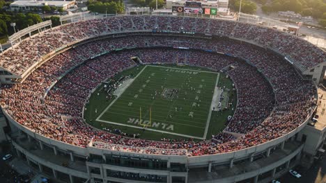 breathtaking aerial view of a packed stadium during an exciting football game, showcasing fans cheering and players competing on the field