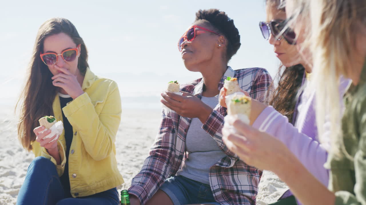 해변에서 피크닉을 하는 다양한 여성 친구들의 행복한 그룹
