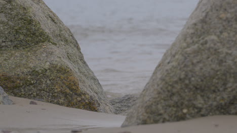 water sloshes against large stones on the seashore