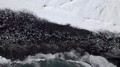 winter landscape with foamy ocean and volcanic black sandy beach