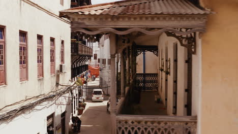 view of zanzibar stone town old narrow street with old wooden balconies and parked cars