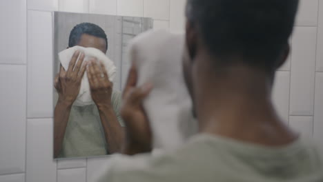 man washing his face in front of a mirror