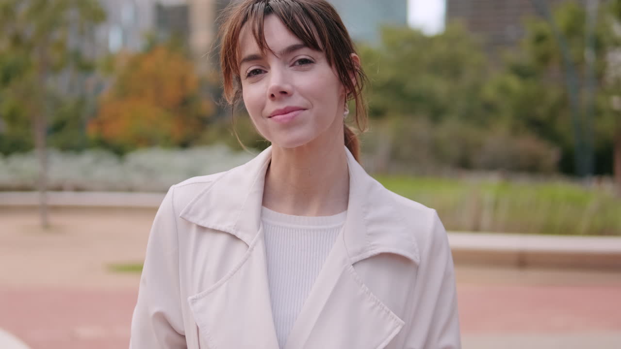 街中でトレンチコートを着て笑顔を見せる女性のポートレート
