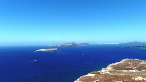 산토리니 그리스의 절벽 너머 먼 열대 섬을 향한 공중 4k 푸른 바다와 하늘 꼭대기 전망