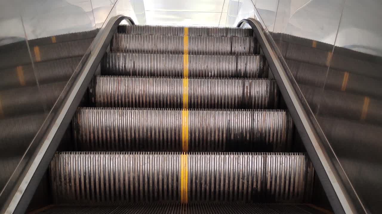 Escalator steps moving upward inside modern building. Perfect for transport, travel, shopping mall, metro and urban lifestyle footage