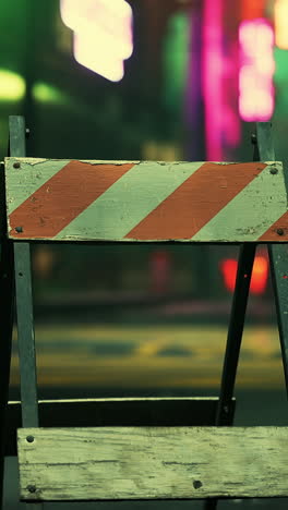 a red and white striped barrier blocking a city street at night.