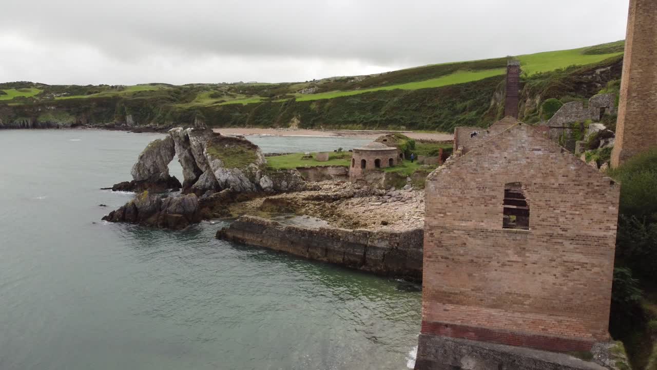 антенна в порте вен, возвышающаяся над остатками заброшенной викторианской промышленной кирпичной фабрики на эродированном побережье англси
