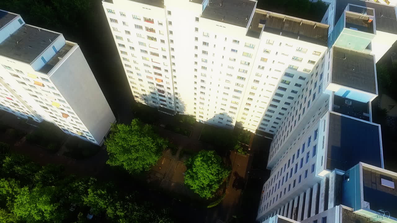 Plano aéreo em drone de cima para baixo avançando sobre edifícios residenciais iluminados em um bairro alemão