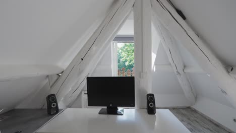 a white room located under the roof, featuring a television and speakers