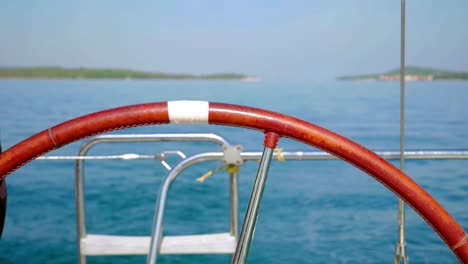 Close-up-of-steering-wheel-of-sailboat-with-blurred-sea-in-background