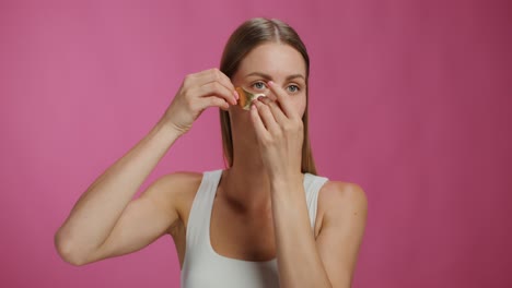 mujer aplicando parches de oro en los ojos para el cuidado de la piel
