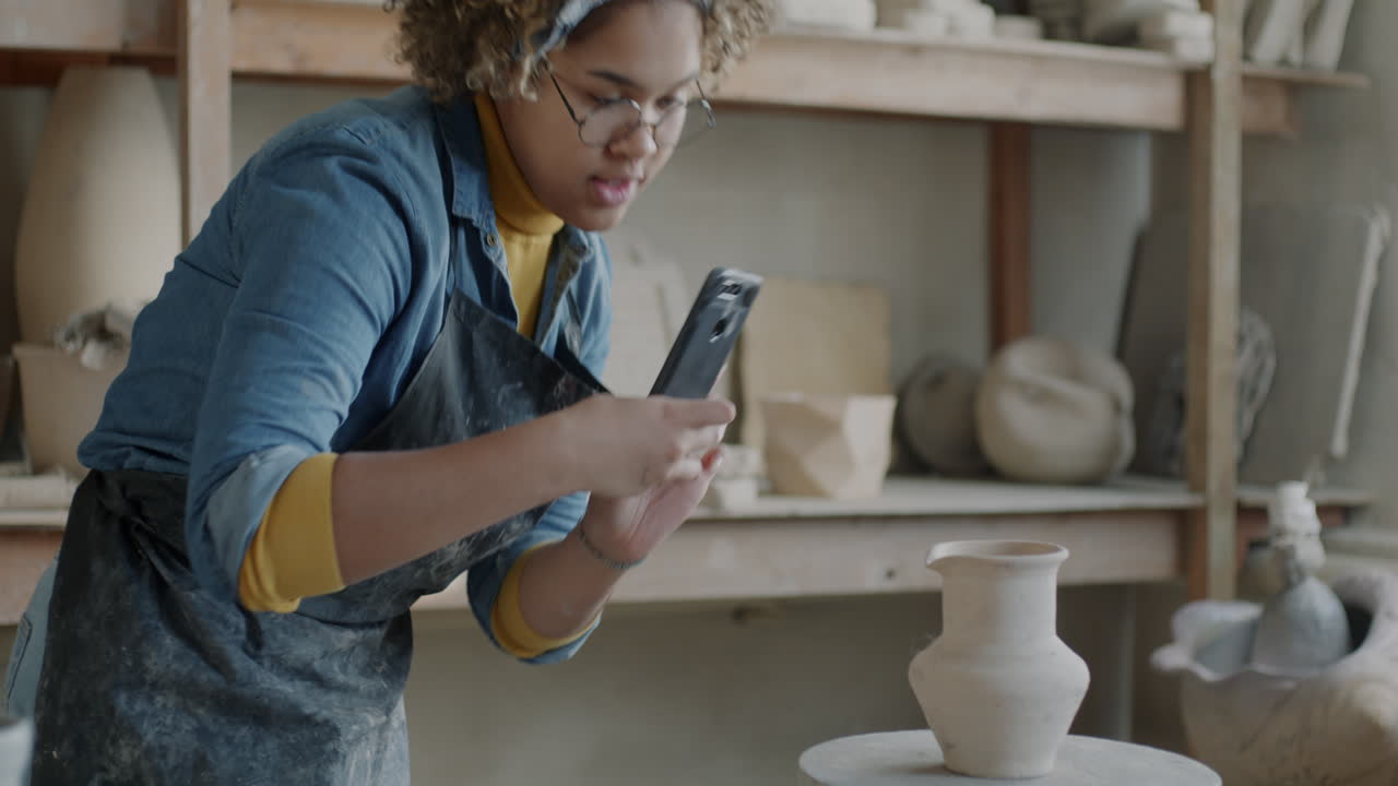 Woman taking photo of pottery in studio