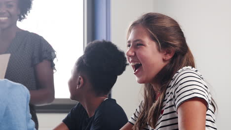 maestro de secundaria y estudiantes riendo durante la lección en el aula