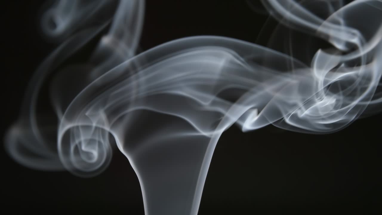 SLOW MOTION: Curly line of smoke lifts up on a dark background