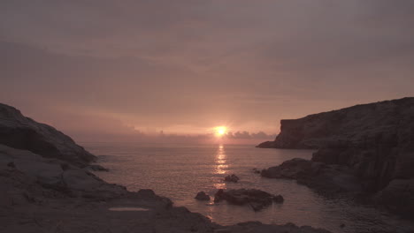 timelapse sunset, from bright to dark, sea, waves are washing on rocks