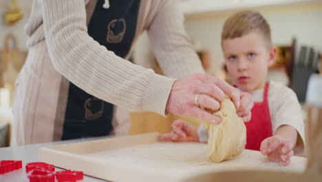 boy watches as his dad kneads bread dough in the kitchen