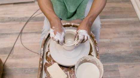 top view of american clerk man modeling ceramic piece on a potter wheel in a workshop