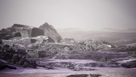 vast barren landscape with rocky formations under a foggy sky at dusk