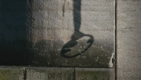 the shadow of an old anchor rope swaying on a concrete pillar