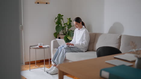 student woman texting laptop working couch. copywriter typing keyboard at sofa