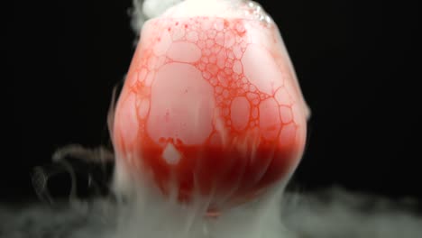 red bubbly liquid in glass with dry ice smoke