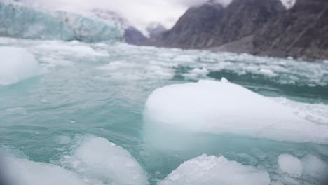 pieces of ice in glacial arctic sea water under glacier in landscape of greenland, point of view, slow motion