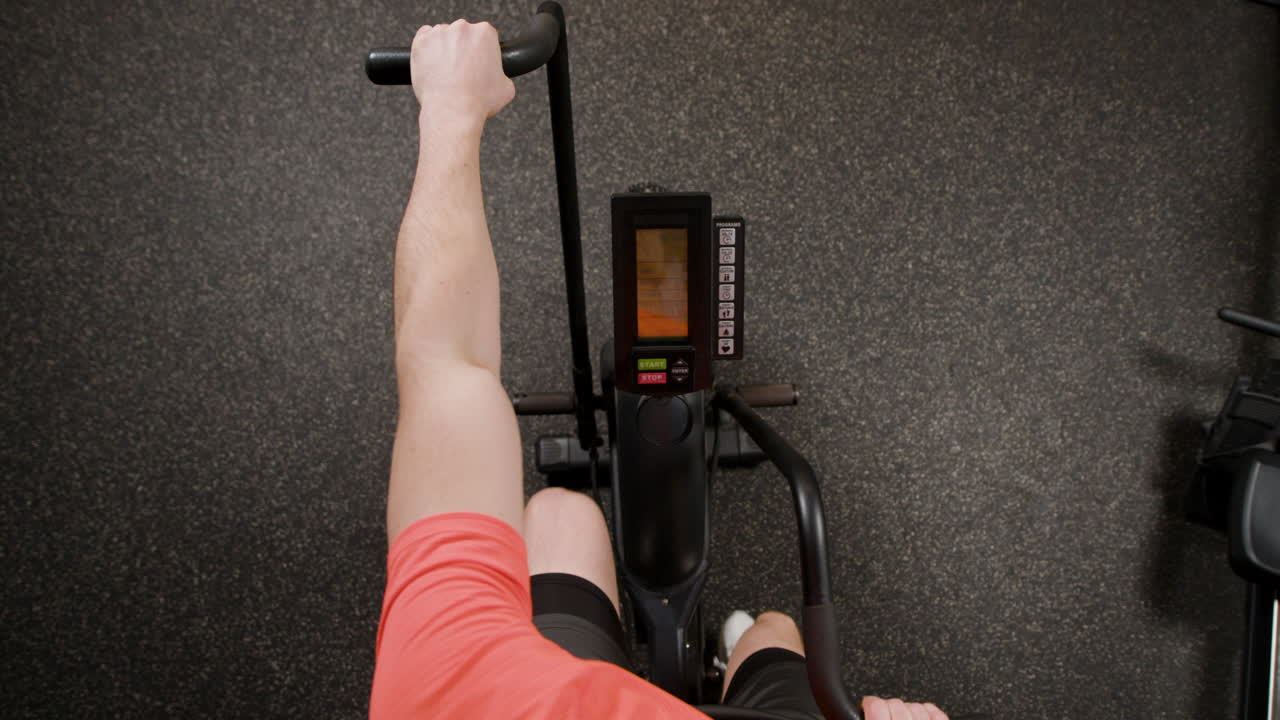 Person Exercising on a Stationary Bike in a Gym