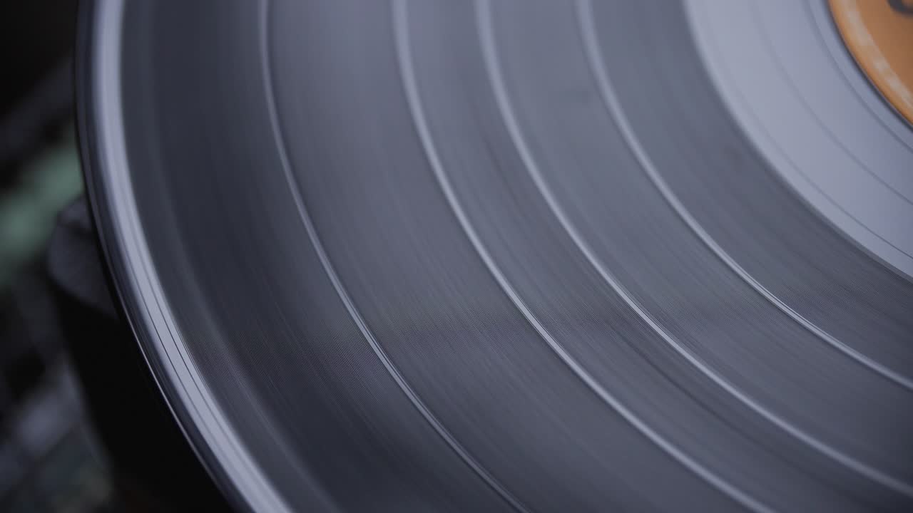 Close-up macro view of black vinyl spinning slowly on a vintage record player