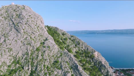 Aerial-reveal-of-waterfront-of-Omis,-sea-and-high-cliffs-in-Croatia